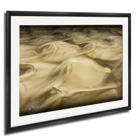 The image is a framed photograph of sand dunes, with a textured, wavy appearance.