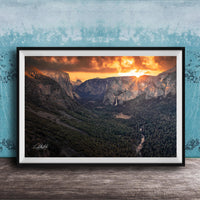 A framed photograph of a breathtaking mountain landscape at sunset, with the sun's rays illuminating the scene and casting a warm glow over the rugged terrain.