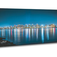 A stunning nighttime cityscape with a skyline of illuminated buildings reflected in the calm waters of a large body of water, creating a mesmerizing and captivating scene.