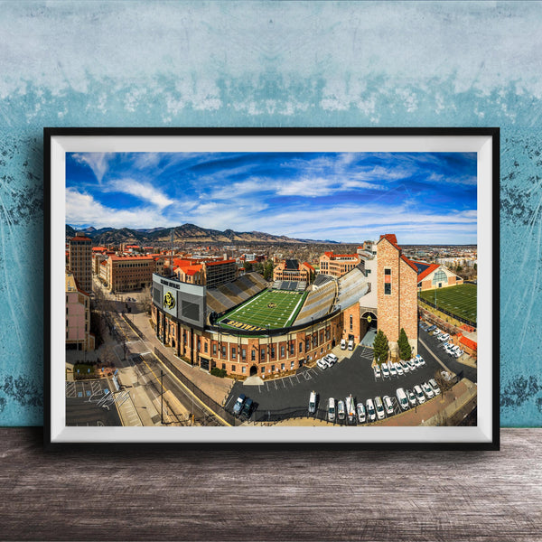The image is a framed aerial view of a city, featuring a football stadium, buildings, and a parking lot.