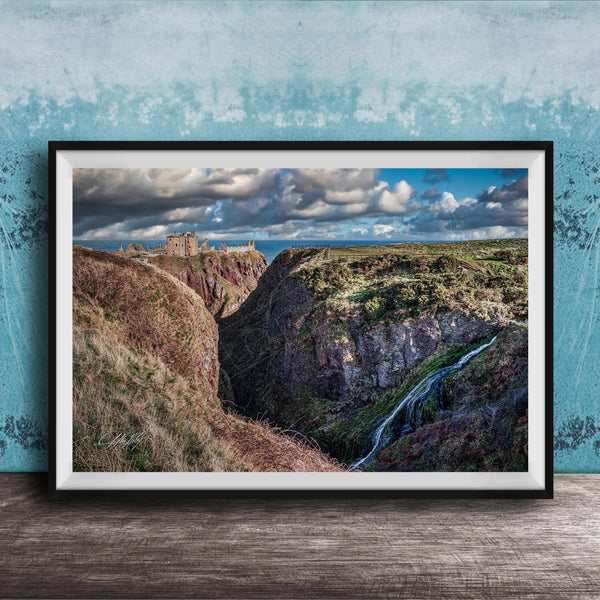 The image is a framed photograph depicting a scenic landscape with a waterfall cascading down a steep cliff face. The photograph is set against a blue wall, creating a striking contrast with the natural elements. The image showcases the beauty of the outdoors and the power of nature.