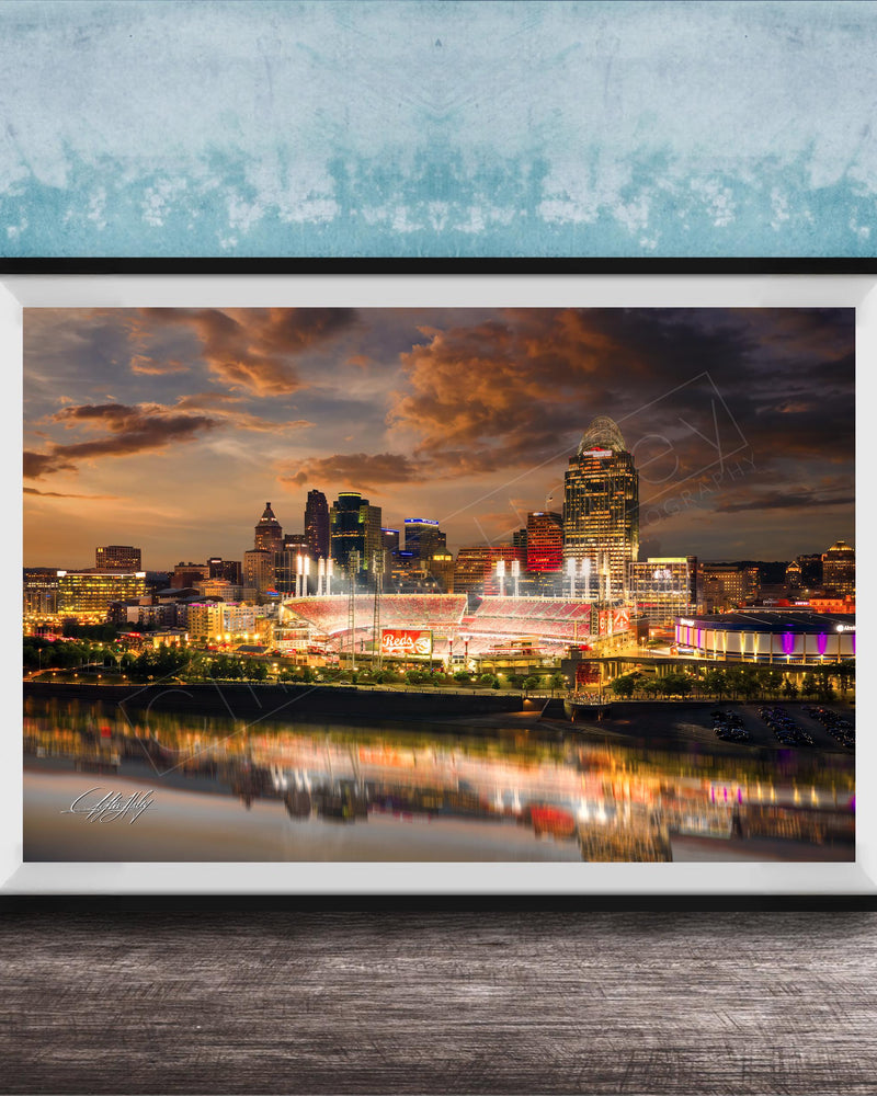 a city skyline at night, with the buildings illuminated and their reflections visible in the water below.