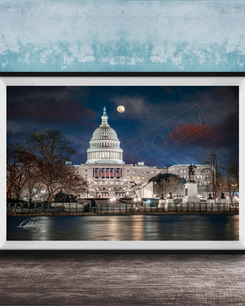 the United States Capitol building at night, with the moon visible in the sky.