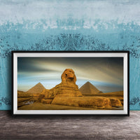 a framed photograph of the Great Sphinx of Giza, a large limestone statue of a mythical creature, in front of the pyramids of Giza in Egypt.