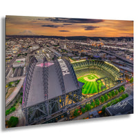 a large baseball stadium with a green field and a large roof structure, set against a backdrop of a city skyline at sunset.