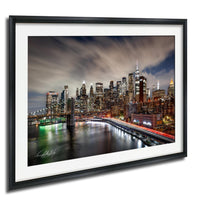 a cityscape at night, with a skyline of tall buildings illuminated by bright lights. The city is reflected in the water below, creating a stunning and vibrant scene.