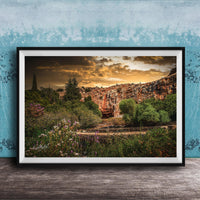 The image is a framed photograph depicting a scenic landscape with a rocky cliff, lush vegetation, and a dramatic sky with clouds.