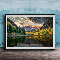 The image is a framed photograph depicting a serene mountain landscape with a lake reflecting the vibrant colors of the sky and surrounding trees.
