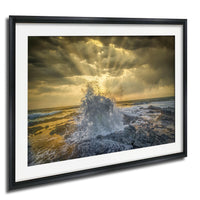 a dramatic scene of a powerful wave crashing against the rocky shore, with the sun's rays shining through the clouds and creating a stunning, golden glow over the ocean.