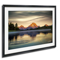 a serene landscape with a mountain range reflected in a calm lake, surrounded by trees and a cloudy sky.