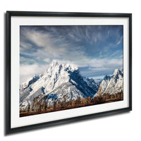 A framed photograph of a snow-capped mountain range against a cloudy sky.