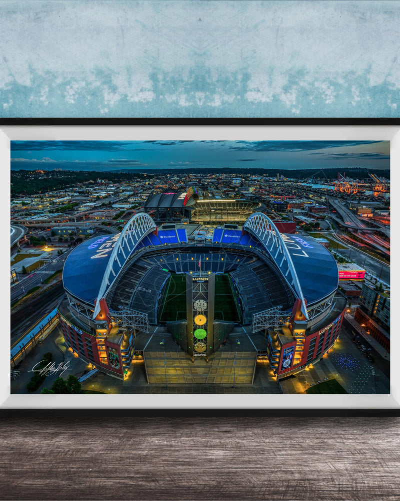 The image is a framed photograph of a large stadium at night, with the stadium's lights illuminating the surrounding cityscape.