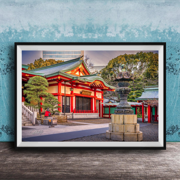 A framed photograph of a traditional Japanese temple with a red roof and white walls, surrounded by trees and a stone fountain.