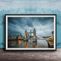 A framed photograph of the iconic Tower Bridge in London, England, with the bridge illuminated against a cloudy sky.