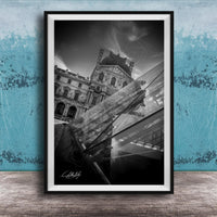 A black and white photograph of the Louvre Museum in Paris, France, with a modern glass structure in the foreground.