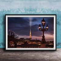 a nighttime cityscape with a tall tower illuminated against a dark sky, with a street lamp in the foreground.