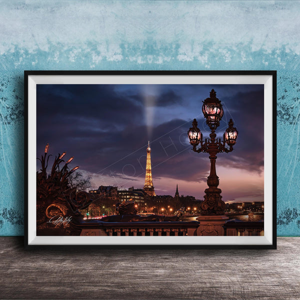 a nighttime cityscape with a tall tower illuminated against a dark sky, with a street lamp in the foreground.
