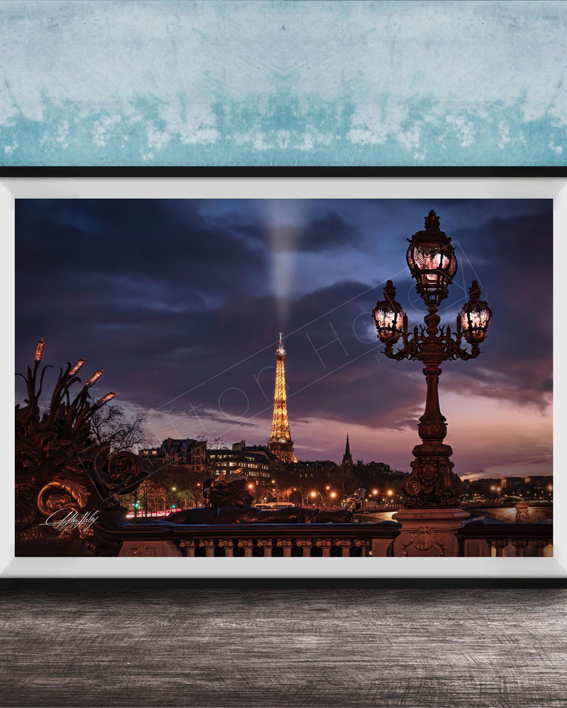 a nighttime cityscape with a tall tower illuminated against a dark sky, with a street lamp in the foreground.