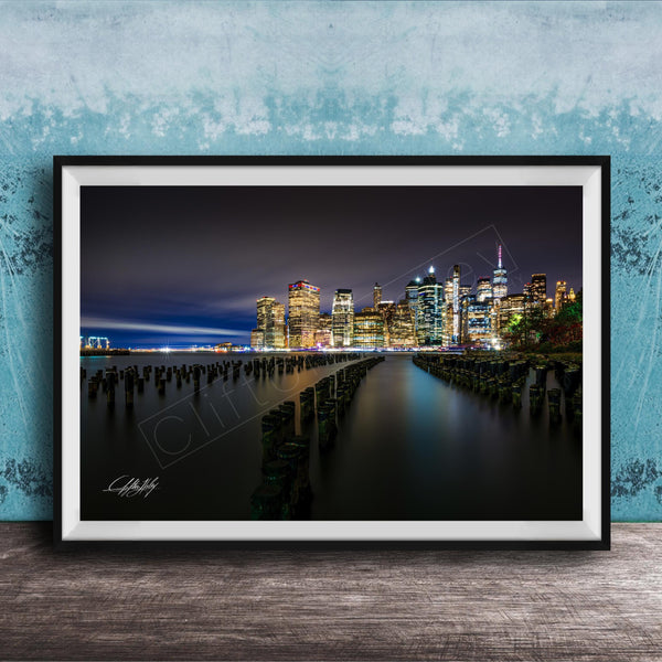 A framed photograph of the New York City skyline at night, with the city's iconic skyscrapers and landmarks illuminated against a dark sky.