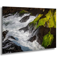 A dramatic landscape featuring a powerful river with white, frothy water flowing over moss-covered rocks.