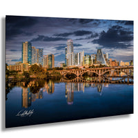 a city skyline with tall buildings reflected in the calm waters of a river or lake.
