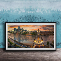 A framed photograph of the skyline of a city at sunset, with the city's iconic landmarks and buildings illuminated against a colorful sky.