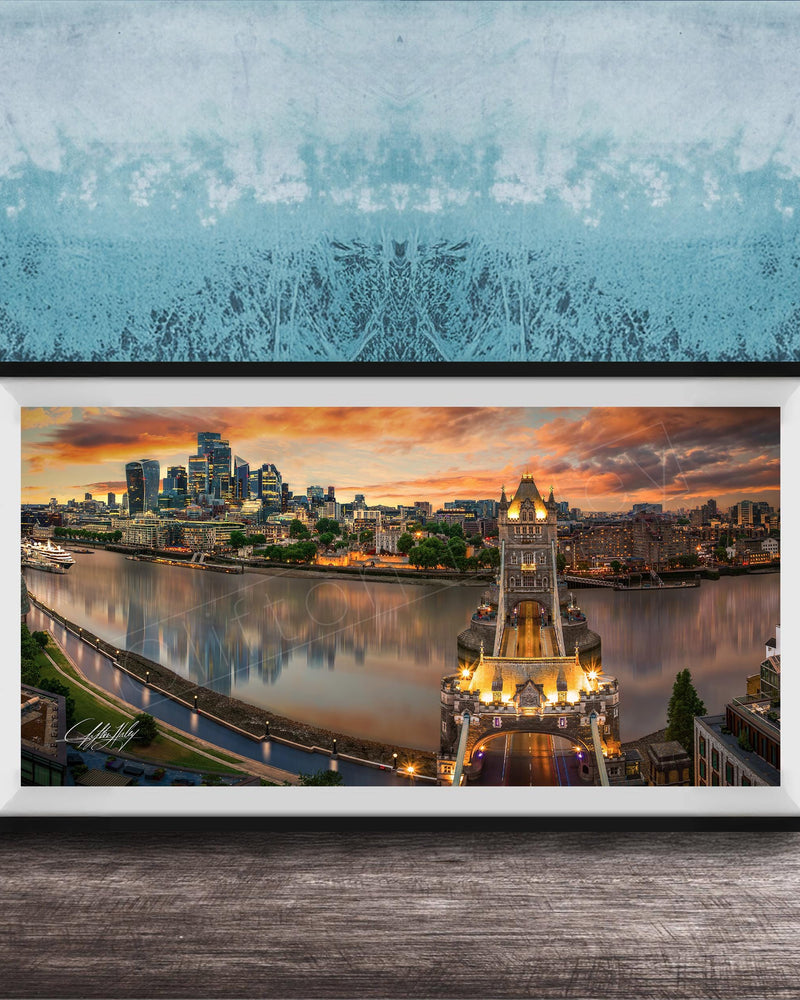 A framed photograph of the skyline of a city at sunset, with the city's iconic landmarks and buildings illuminated against a colorful sky.