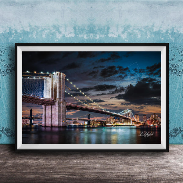 A framed photograph of the Brooklyn Bridge at night, with its iconic towers and suspension cables illuminated against a dark sky.