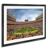 A framed photograph of a crowded football stadium during a game, with the field and stands filled with spectators.