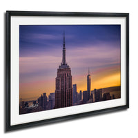 the iconic Empire State Building in New York City, with its distinctive spire and silhouette against a vibrant sunset sky.