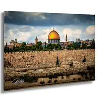 the Dome of the Rock, a prominent landmark in Jerusalem, Israel. The golden dome of the mosque stands out against the cloudy sky, surrounded by lush greenery and the city's historic buildings.