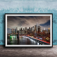 A framed photograph of the New York City skyline at night, with the city's iconic landmarks and buildings illuminated against a dark sky.