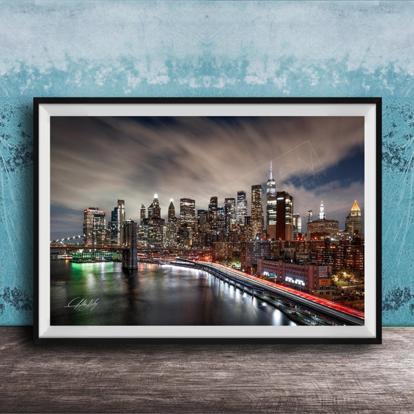A framed photograph of the New York City skyline at night, with the city's iconic landmarks and buildings illuminated against a dark sky.