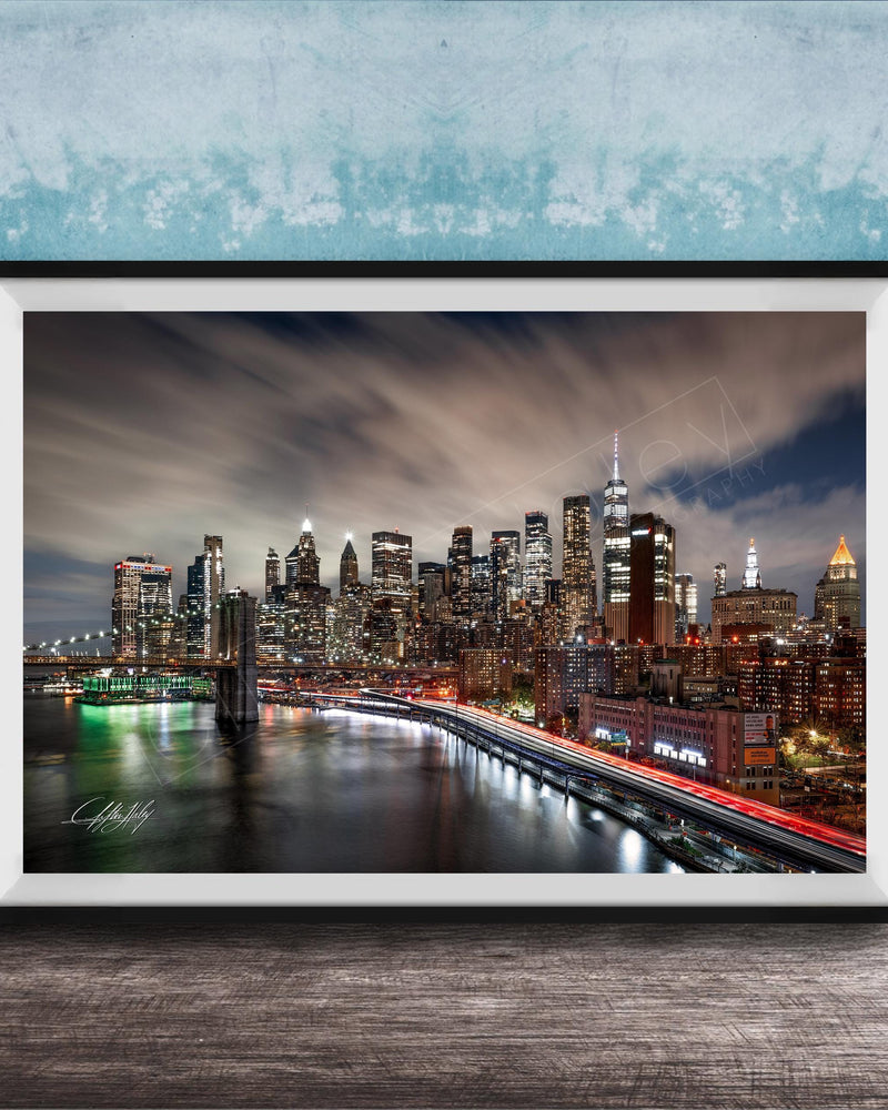 A framed photograph of the New York City skyline at night, with the city's iconic landmarks and buildings illuminated against a dark sky.