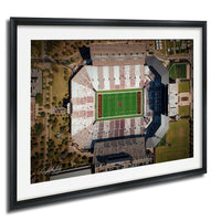 The image is an aerial view of a football stadium with a green field and surrounding buildings.