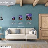 a living room with a white sofa and a wooden door. There are three framed pictures of different sizes displayed on the wall above the sofa.