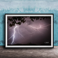 A framed photograph of a dramatic lightning storm with bolts of light illuminating the dark sky.