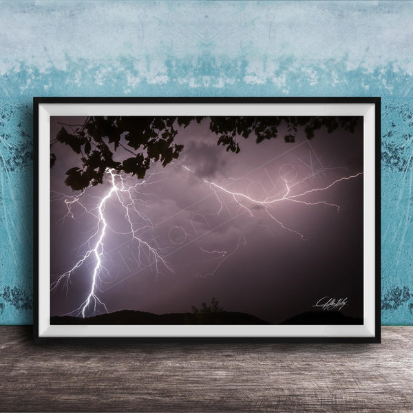 A framed photograph of a dramatic lightning storm with bolts of light illuminating the dark sky.