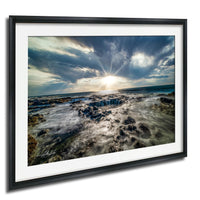 a dramatic scene of a rocky coastline with crashing waves, set against a cloudy sky with the sun peeking through the clouds.