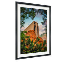 A framed photograph depicting a large, modern building with a distinctive architectural design, surrounded by lush greenery and a mountainous landscape.