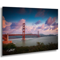 the Golden Gate Bridge, a famous suspension bridge in San Francisco, California, with its distinctive red towers and cables spanning the San Francisco Bay. The sky is filled with clouds, creating a dramatic backdrop for the iconic structure.