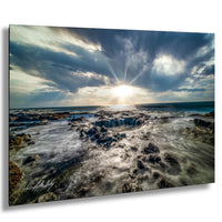 a rocky coastline with crashing waves, a bright sun shining through the clouds, and a dramatic sky.