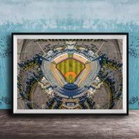 The image is an aerial view of a baseball stadium, featuring a large field surrounded by parking lots and other structures.