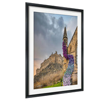 A framed photograph of Edinburgh Castle, a historic castle located in Scotland, with a colorful flower arrangement in the foreground.