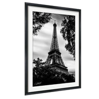 A black and white photograph of the Eiffel Tower in Paris, France, framed and displayed on a wall.