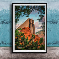A framed photograph of a large, modern church with a distinctive cross-shaped roof, set against a backdrop of red rock formations and lush greenery.