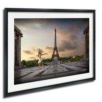 A woman in a white dress is dancing in front of the Eiffel Tower in Paris, France, with a dramatic sky in the background.