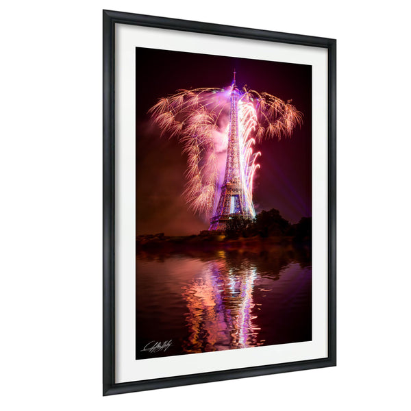 a large, illuminated tower with a vibrant display of fireworks in the night sky, reflected in the water below.