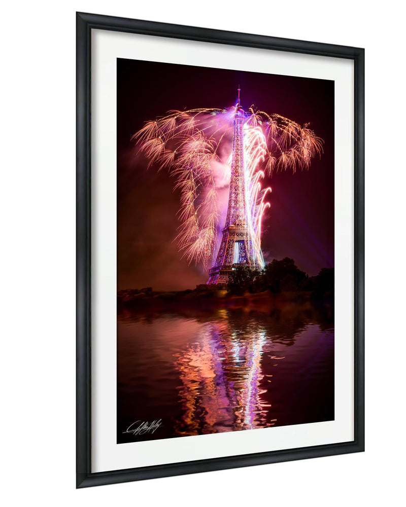 a large, illuminated tower with a vibrant display of fireworks in the night sky, reflected in the water below.