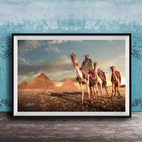 A framed photograph depicting a camel caravan in front of the iconic pyramids of Giza, Egypt, with a man riding one of the camels.